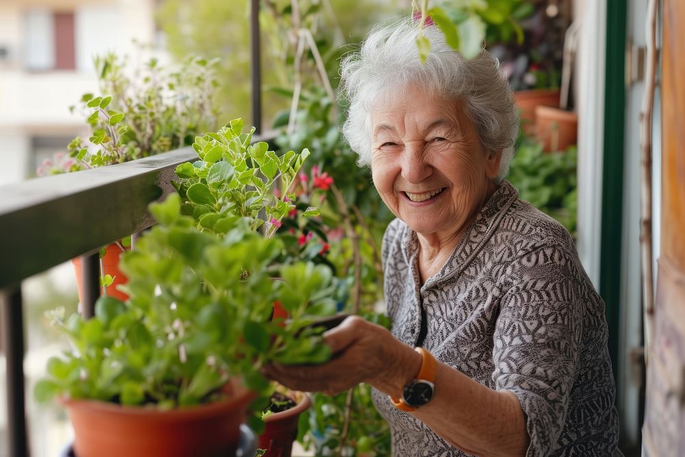 Older woman smiling warmly while tending to her potted plants on a sunny balcony architecture cheerful outdoors. AI…