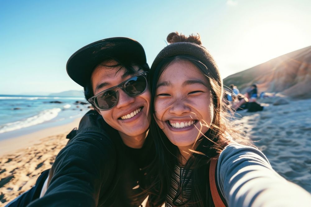 Asian couple selfie at the beach sunglasses laughing portrait.