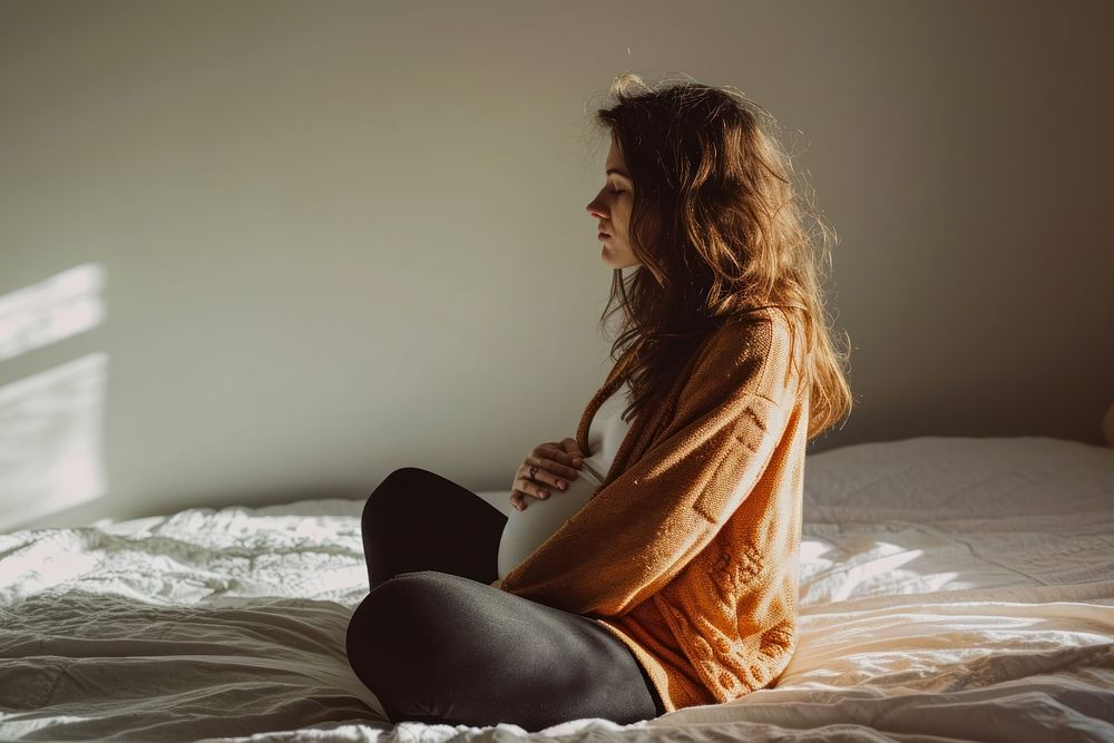 Pregnant woman sitting adult bed.