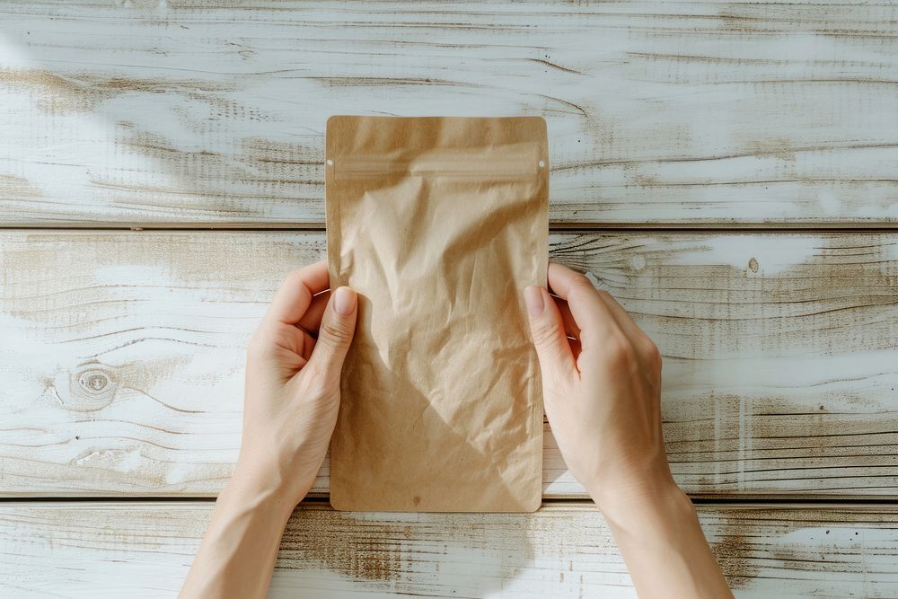 Person holding paper coffee bag wood hand indoors.