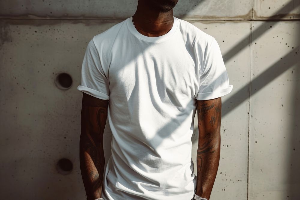 Black man wearing t-shirt standing with clean concrete background sleeve white skin.