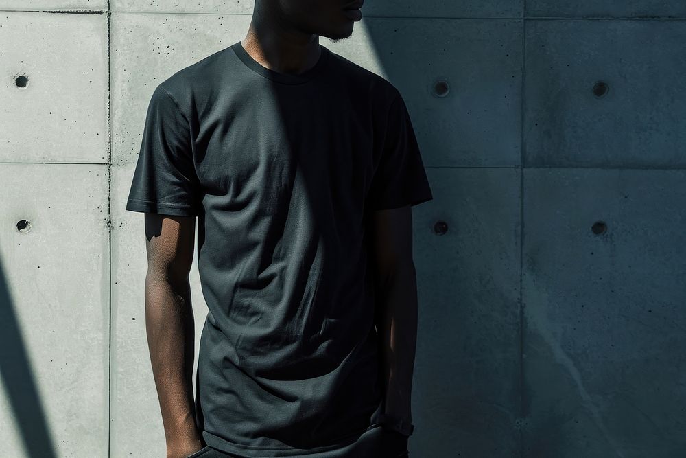 Black man wearing t-shirt standing with clean concrete background sleeve architecture portrait.
