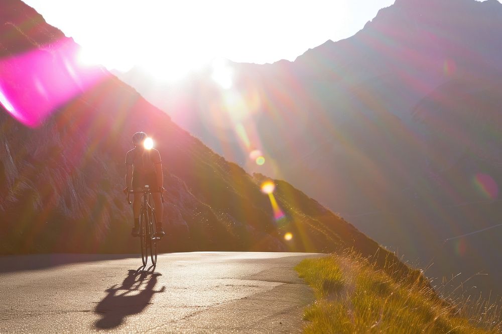Cyclist riding up in high mountains light sunlight outdoors.