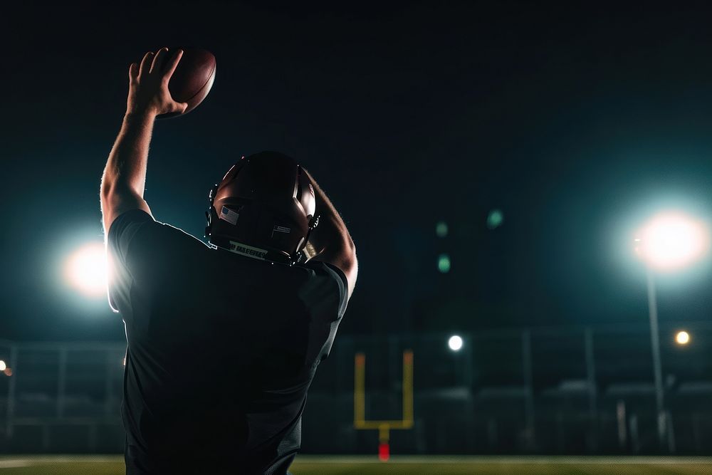 Professional football quarterback night throwing outdoors.