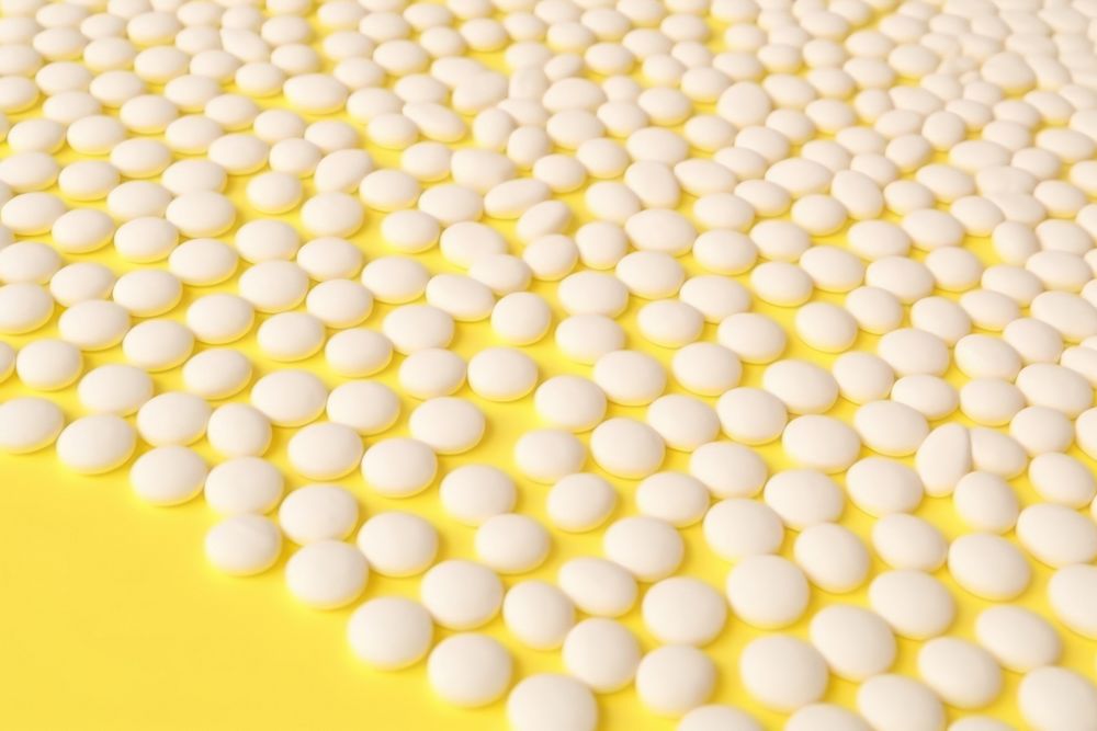 White pills or capsules lies in rows diagonal on yellow background backgrounds microbiology repetition. AI generated Image…