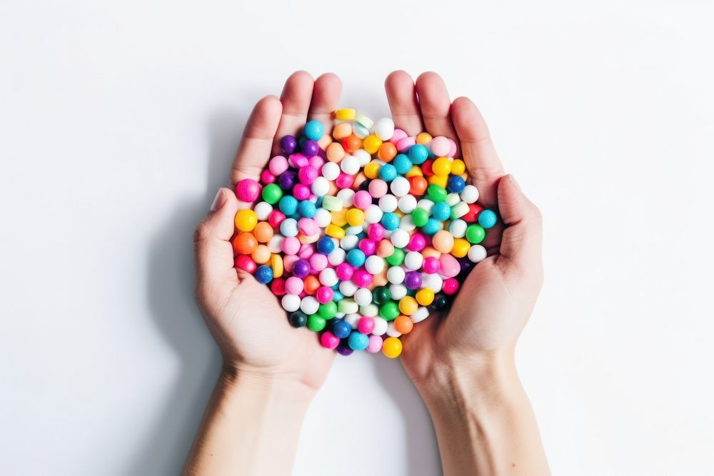 Colorful pills and medicines in the hand confectionery sprinkles candy. AI generated Image by rawpixel.