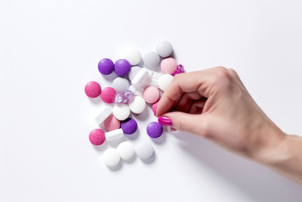 Close up of young female hands holding pack and pills capsules taking medicine for relieving female period white background…