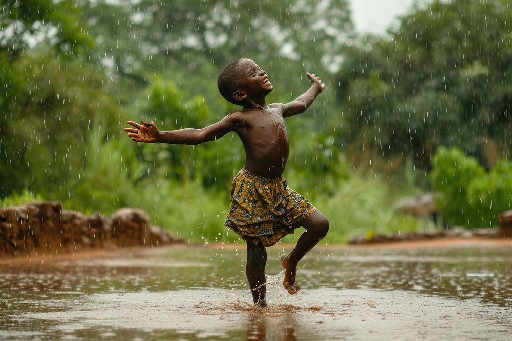 African boy dancing on the rain outdoors happiness splashing.
