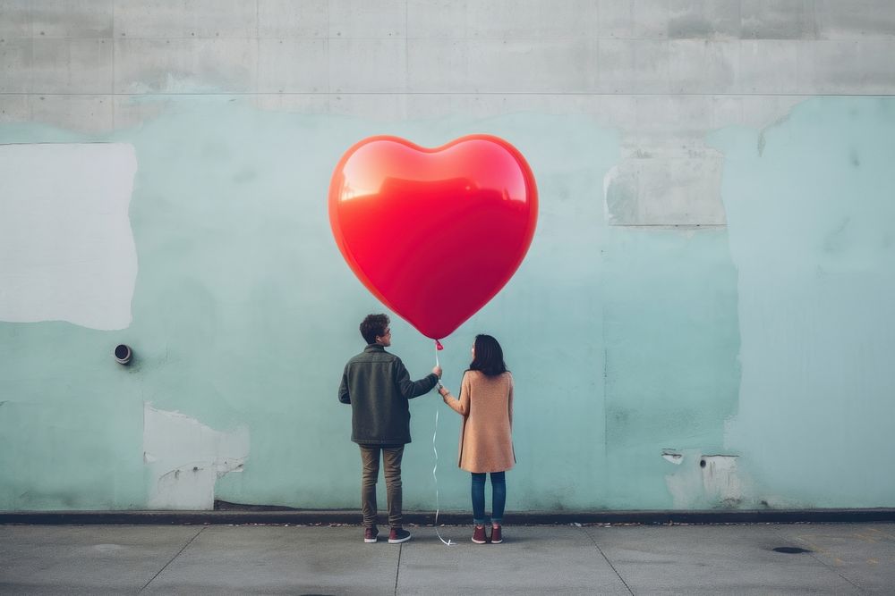 LGBT couple holding a colorful heart shape air balloon adult wall togetherness. AI generated Image by rawpixel.
