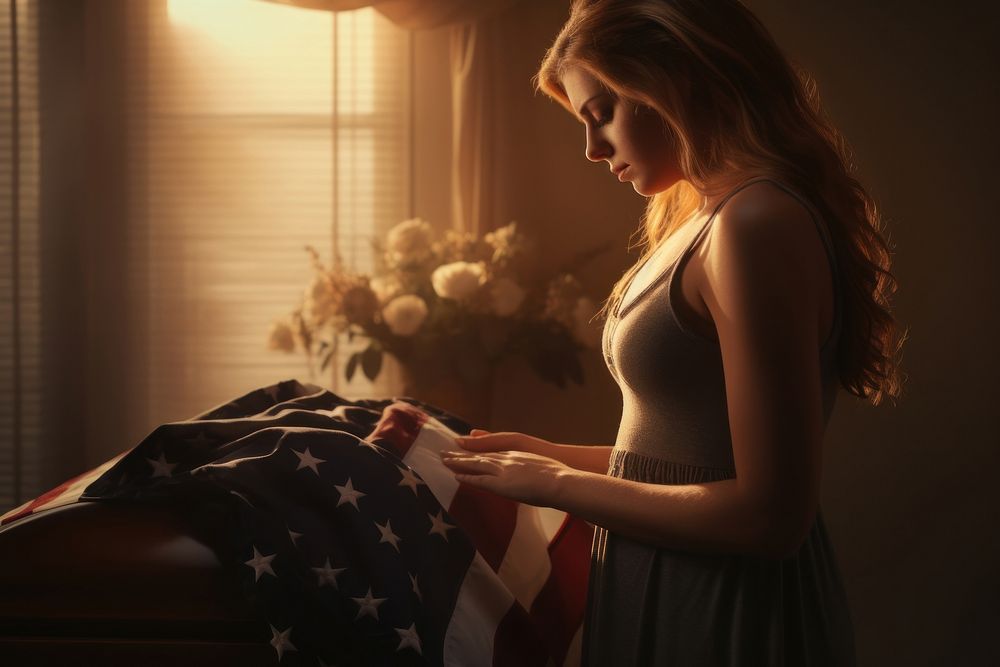 Pregnant wife grieving over casket draped funeral adult flag.
