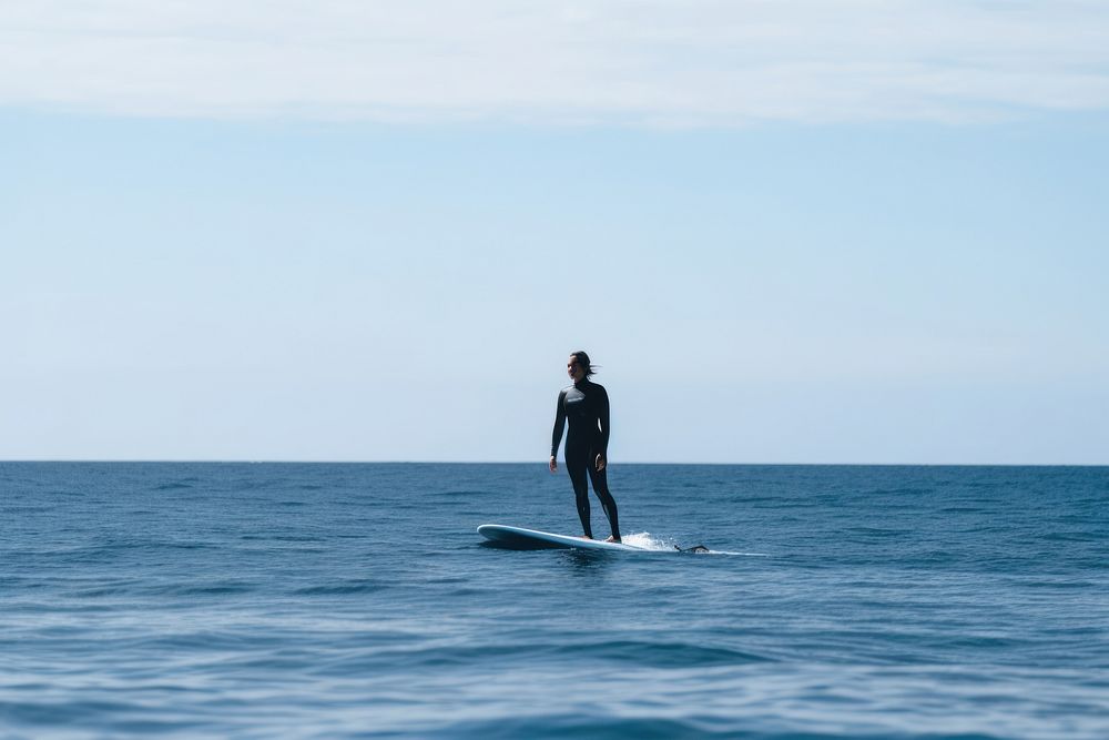 Young women wearing bodysuit on surfboard during a wave in the sea oars recreation standing.