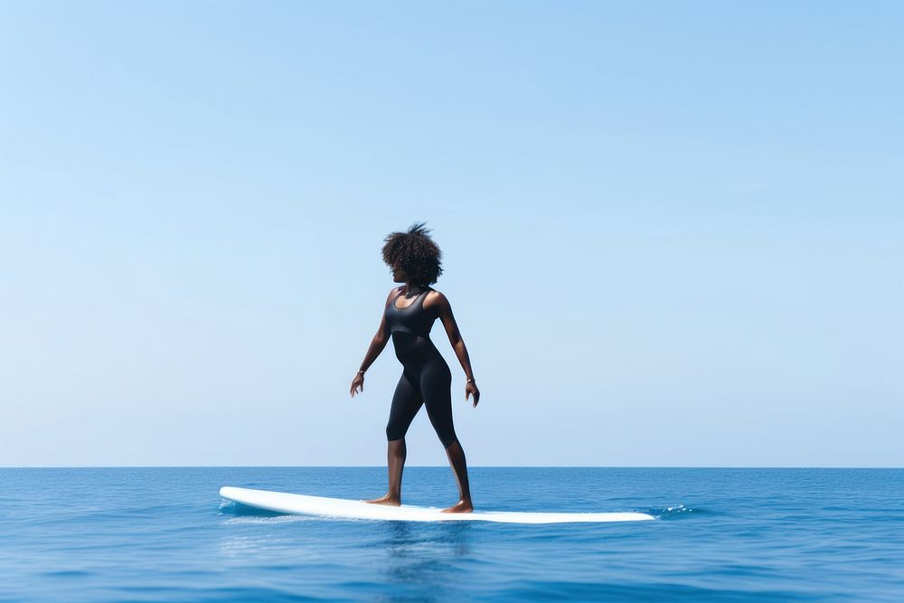 Young women wearing bodysuit on surfboard during a wave in the sea outdoors surfing sports.
