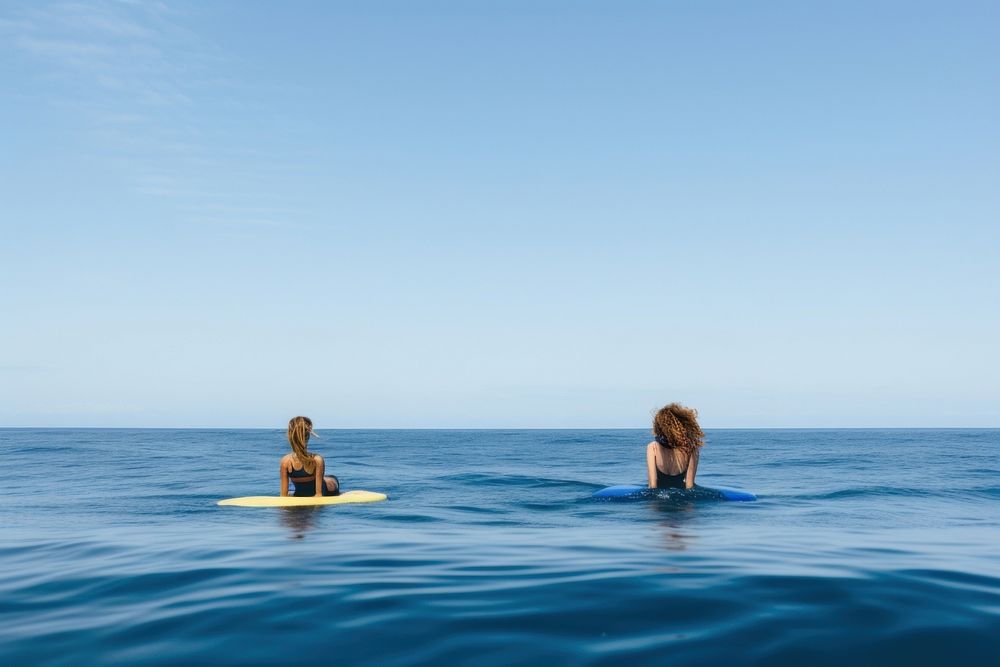 Young women wearing bodysuit lying down on surfboard during a wave in the sea recreation swimming swimwear.