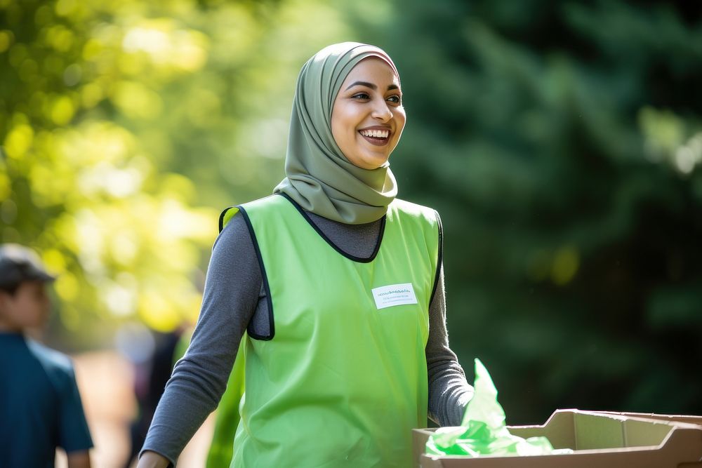 Muslim woman volunteer staff outdoors holding green.