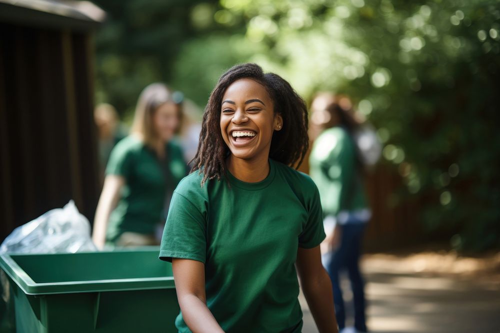 A black woman volunteer staff laughing outdoors holding.