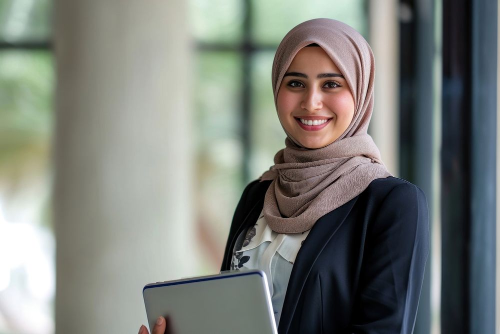 Muslim business woman holding a laptop smiling smile scarf. AI generated Image by rawpixel.