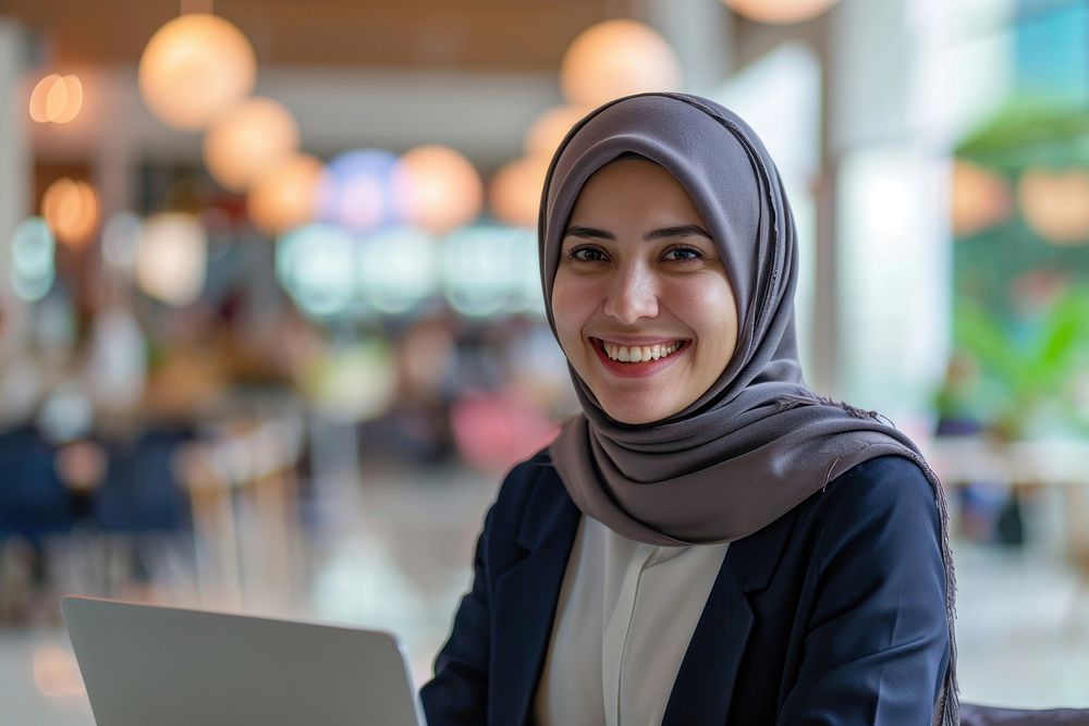 Muslim business woman holding a laptop computer smiling scarf. AI generated Image by rawpixel.