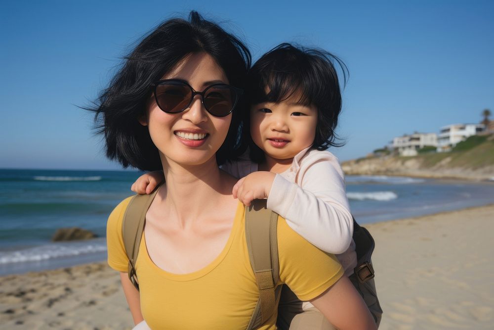 Asian mom piggyback baby on a beach photography sunglasses portrait.