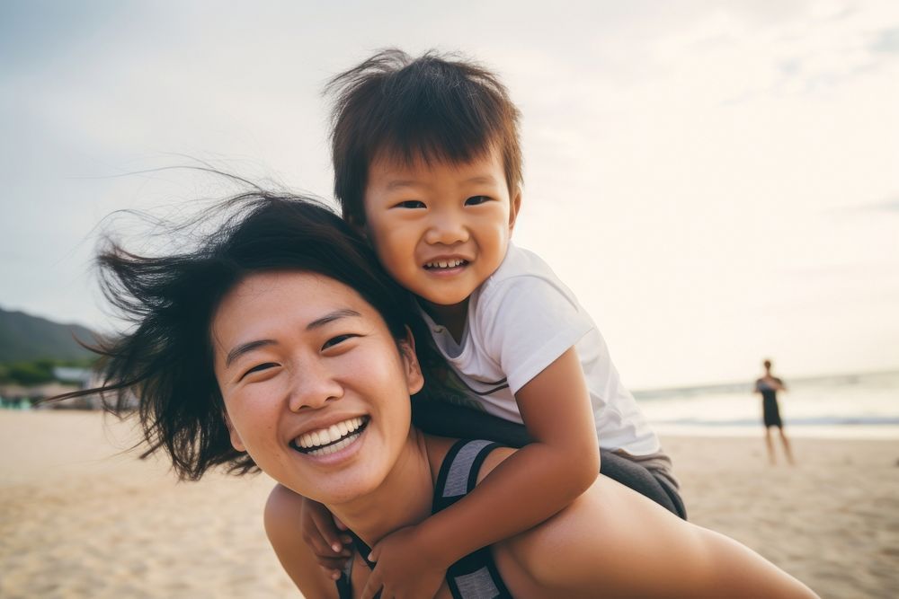 Asien mom piggyback baby on a beach photography laughing portrait.