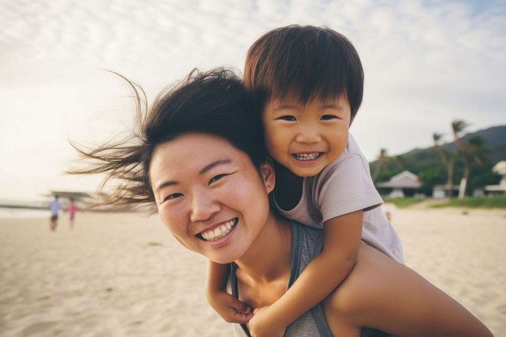 Asien mom piggyback baby on a beach photography laughing portrait.