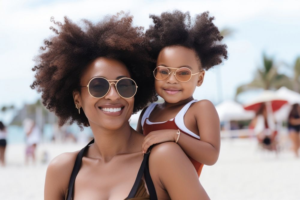 Black mom piggyback baby on a beach photography sunglasses portrait.