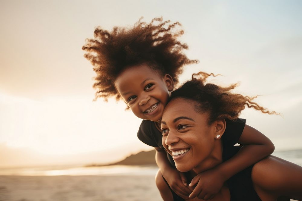 Black mom piggyback baby on a beach photography laughing portrait.