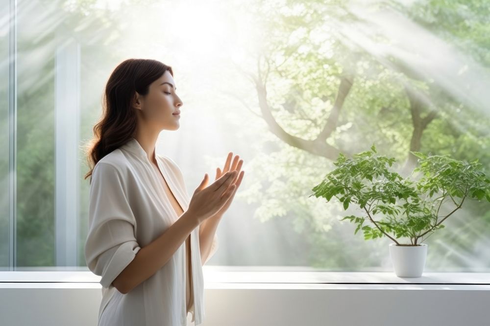 A women holding her hands on her chest and take a deep breath in morning plant adult contemplation.