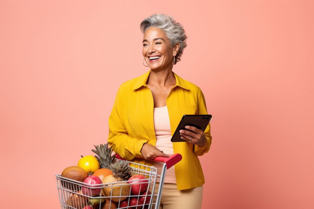 Happy Latin senior woman holding a shopping basket adult retirement technology.