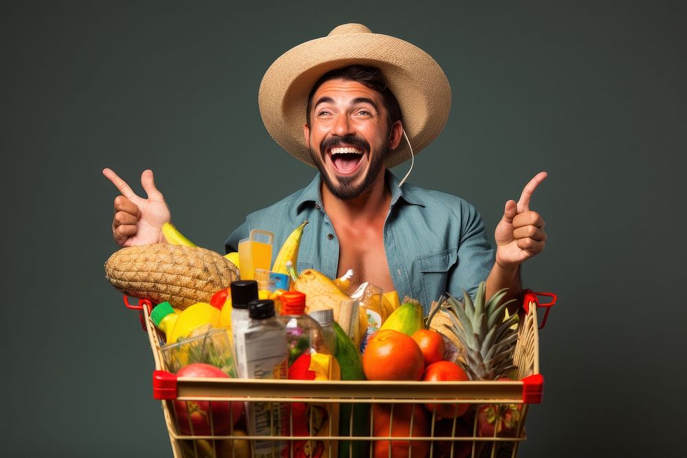 Happy Mexican man holding a shopping basket full of products while he uses a mobile app pineapple laughing adult.