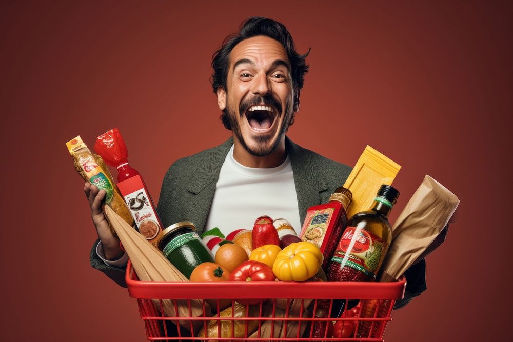 Happy Mexican man holding a shopping basket full of products while he uses a mobile app bottle adult food.