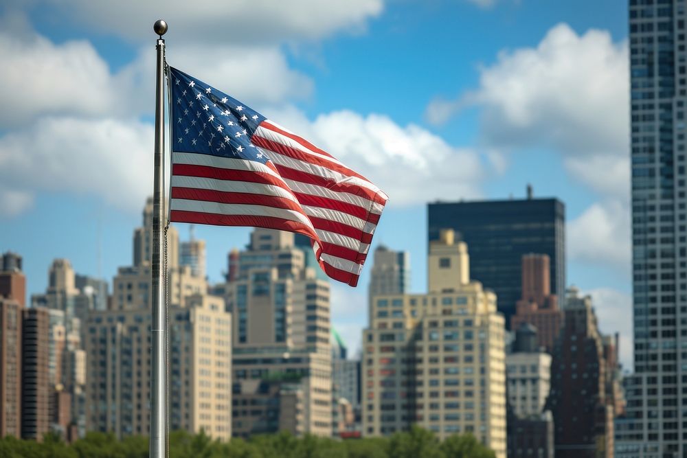 Close up of The America flag against New York City skyline city independence architecture.