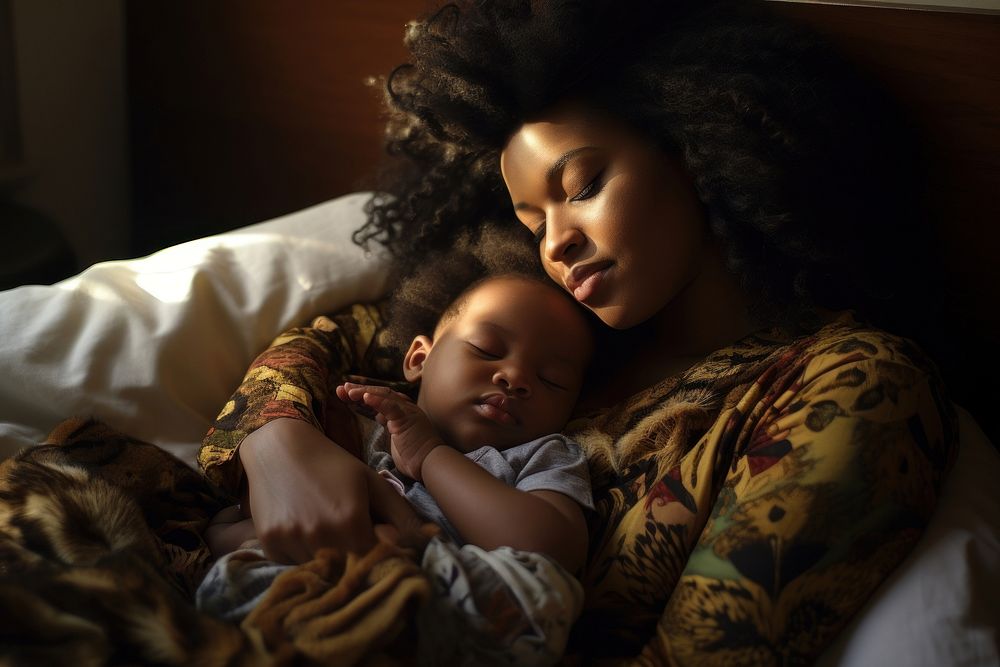 Black mom holding sleeping infant portrait adult photo.