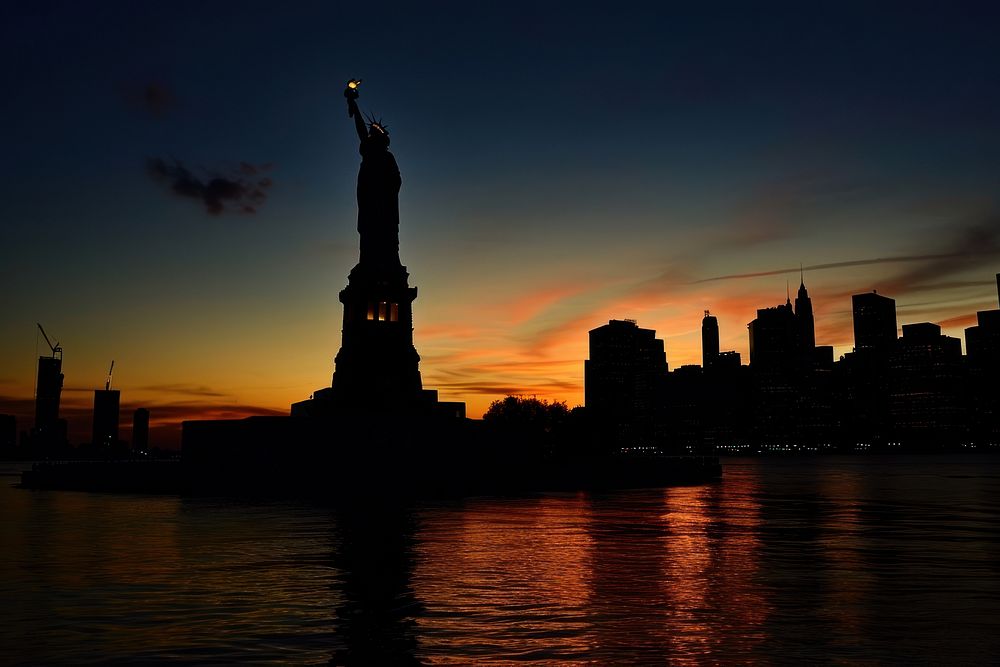 The Statue of Liberty against New York City skyline silhouette landmark evening.