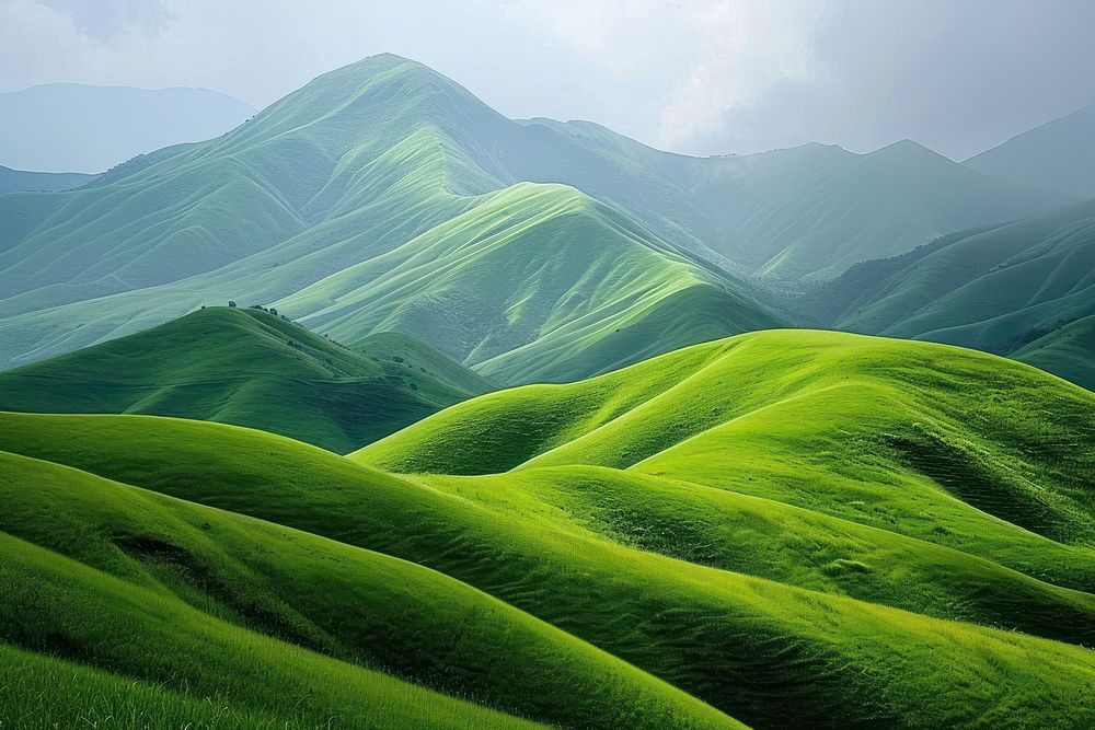 Serene green hills against mountain landscape grassland outdoors.