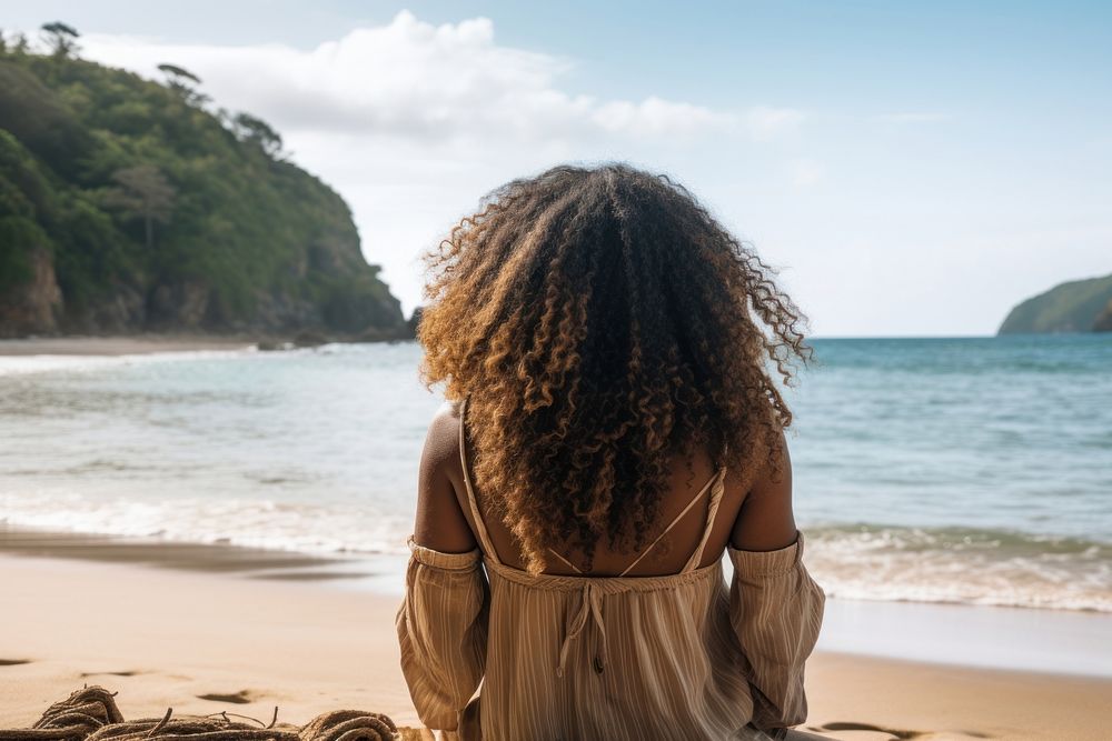 Chubby African american woman with dreadlock hair sit on a beach looking at the sea summer adult back.