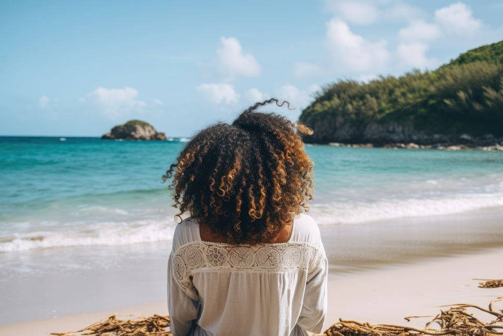 Chubby African american woman with dreadlock hair sit on a beach looking at the sea summer adult back.