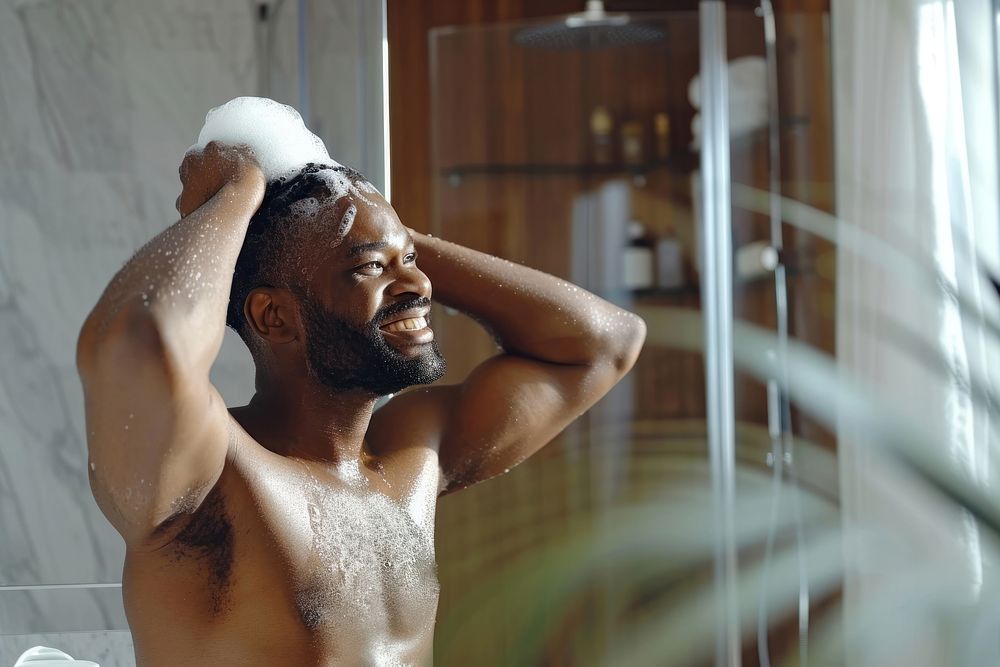 A happy black guy washing hair bathroom shower adult.