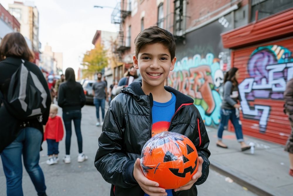 A kid with funny costume holding halloween pumpkin football sports adult.