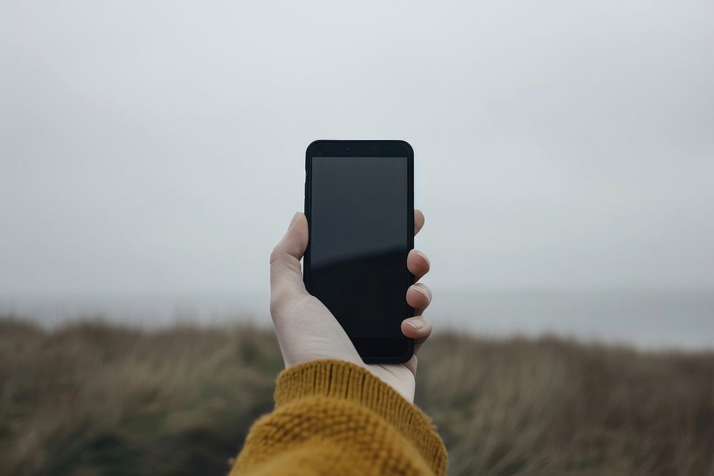 Hand holding smart phone outdoors selfie photo.
