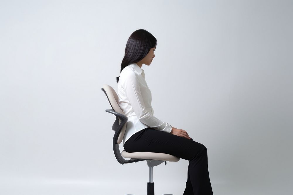 An east asian woman suffering from work sitting chair furniture.