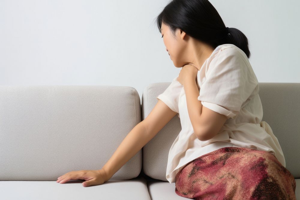An east asian woman suffering from sickness sitting furniture adult.