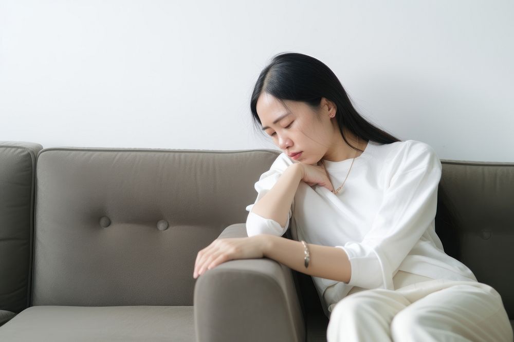 An east asian woman suffering from sickness furniture worried sitting.