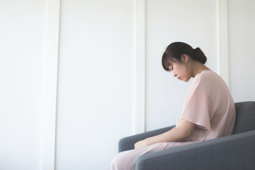 An east asian woman suffering from sickness sitting worried adult.