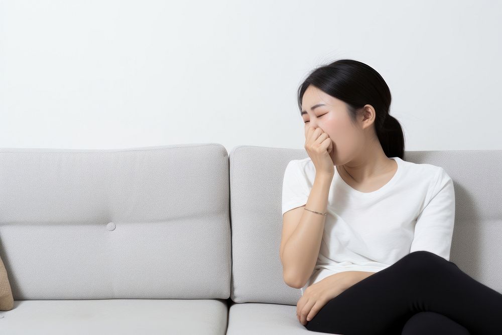 An east asian woman suffering from sickness furniture worried sitting.