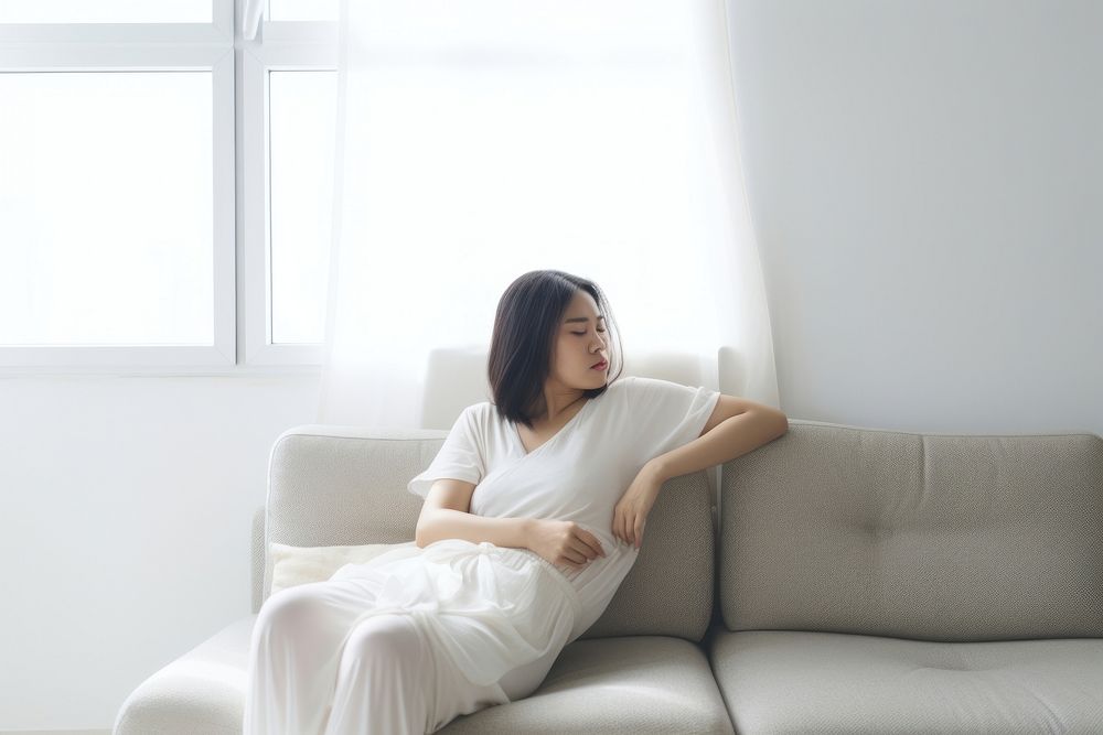 An east asian woman suffering from sickness sitting furniture adult.