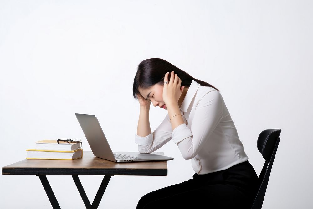 An east asian woman suffering from a headache furniture computer worried.