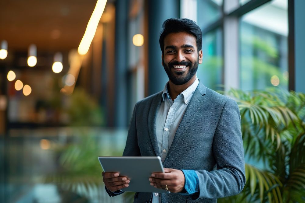 Indian business man smiling whild holding a tablet computer office adult. AI generated Image by rawpixel.