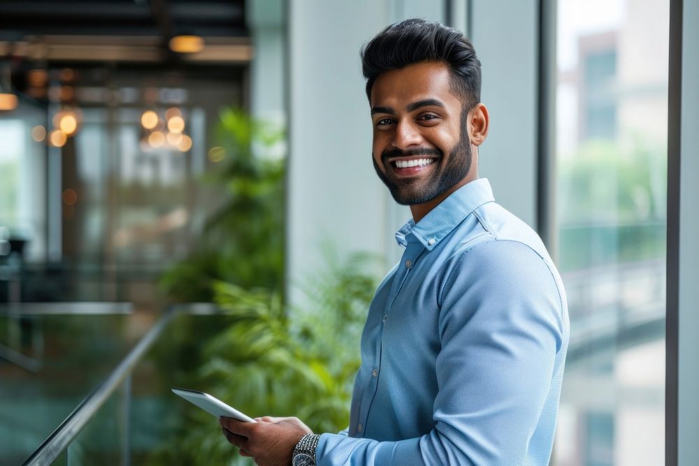 Indian business man smiling whild holding a tablet office smile adult. AI generated Image by rawpixel.