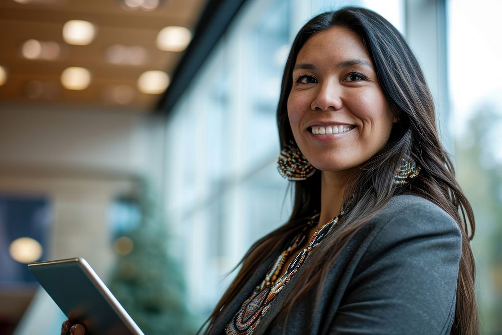 Native american business woman smiling whild holding a tablet adult smile architecture. AI generated Image by rawpixel.