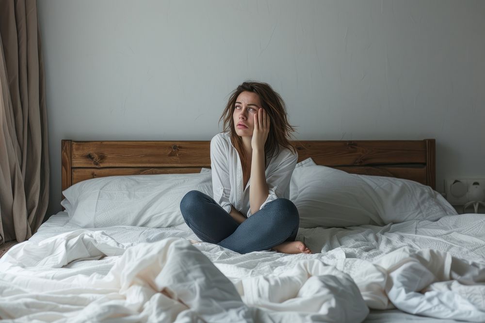 Woman is sitting on the floor in bed furniture mattress worried.